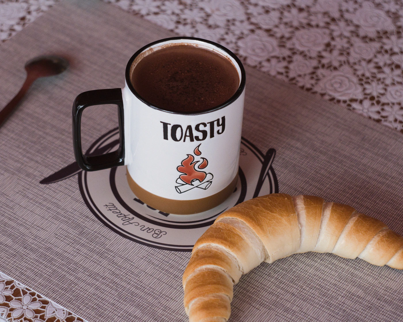 A warm drink and a croissant on a breakfast table
